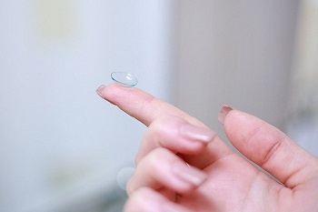 A contact lens on a woman's outstretched hand